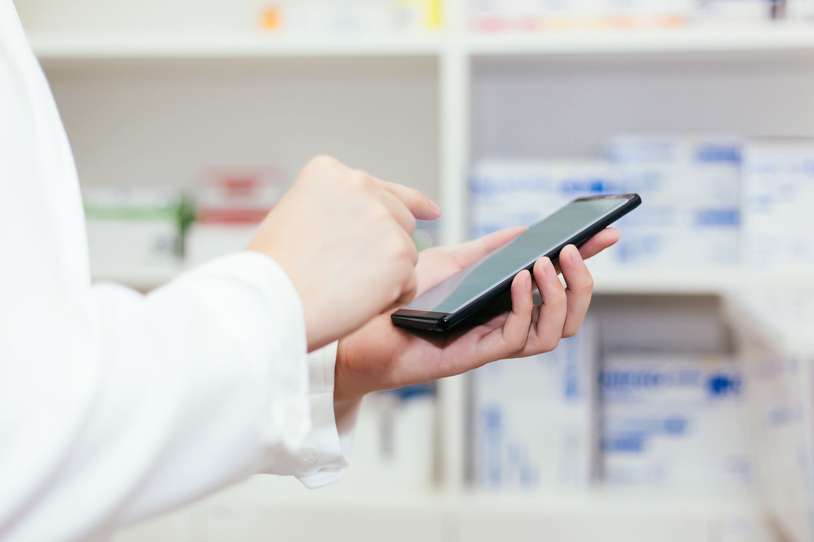 E-Rezepte per Handy Apotheker hält ein Handy in der Hand und tippt mit einem Finger auf den Bildschirm